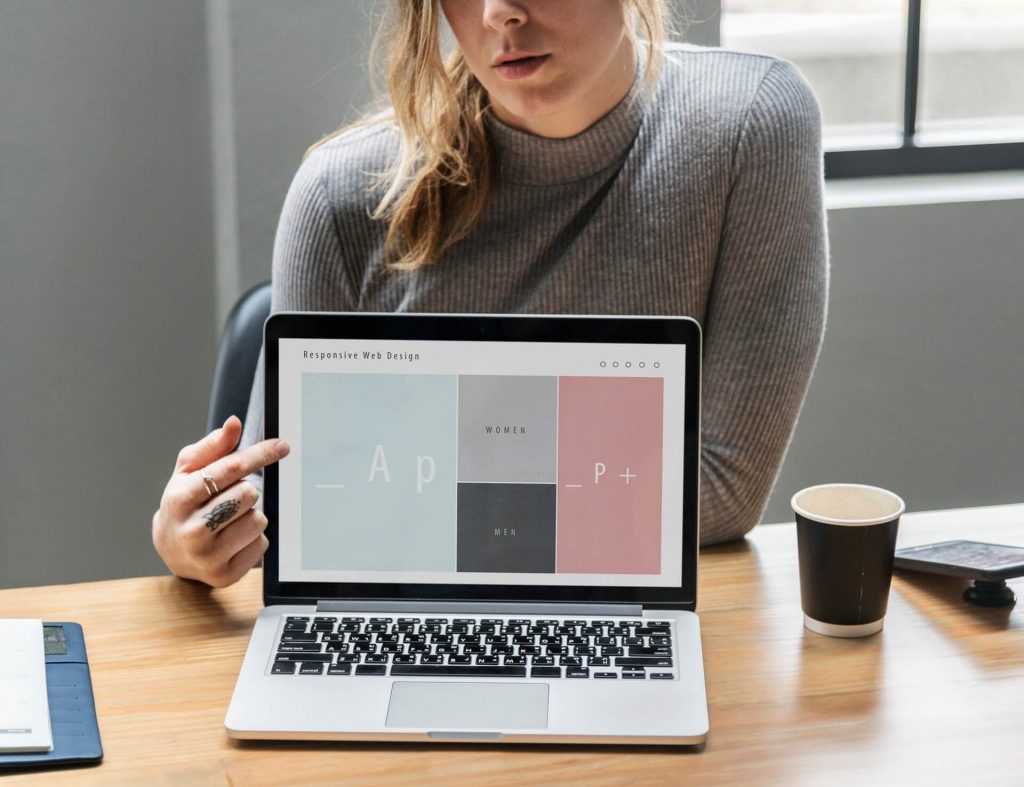 A woman pointing at a laptop screen.