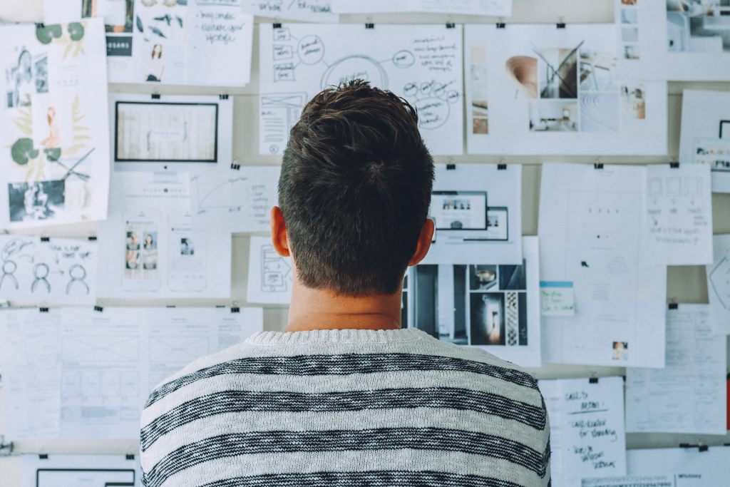 A man staring at a wall filled with papers.