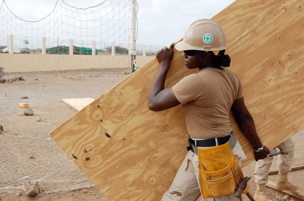 A construction worker carrying some wood.