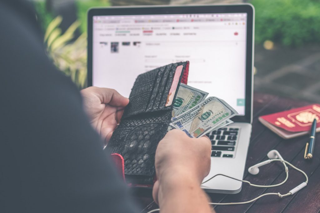 Man with his wallet in front of his computer.