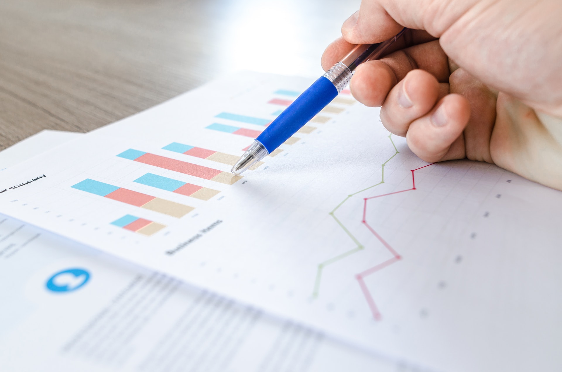 A person's hand holding a pen to an analytics chart.