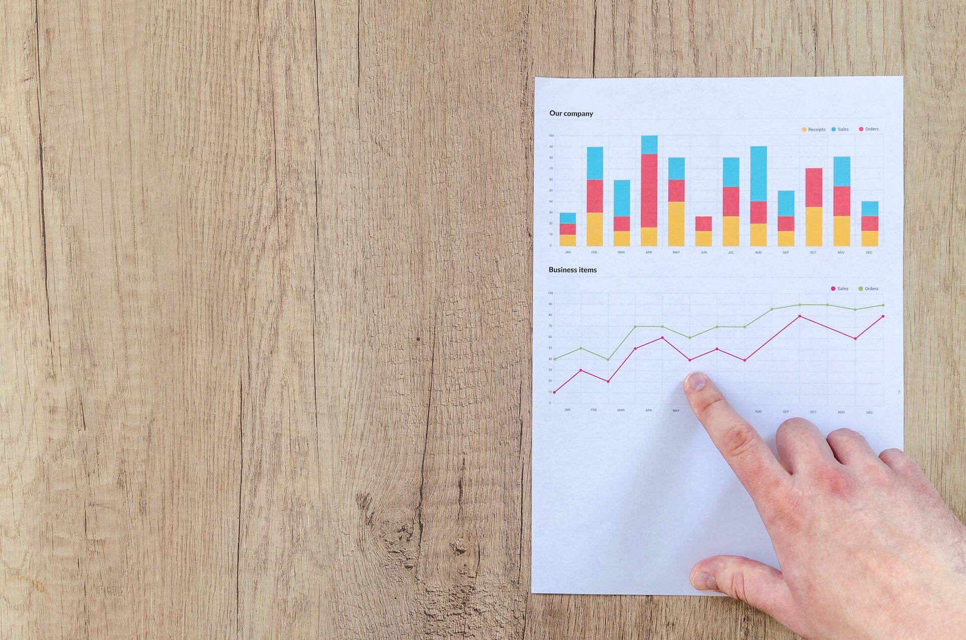 Hand pointing at graphs and charts.