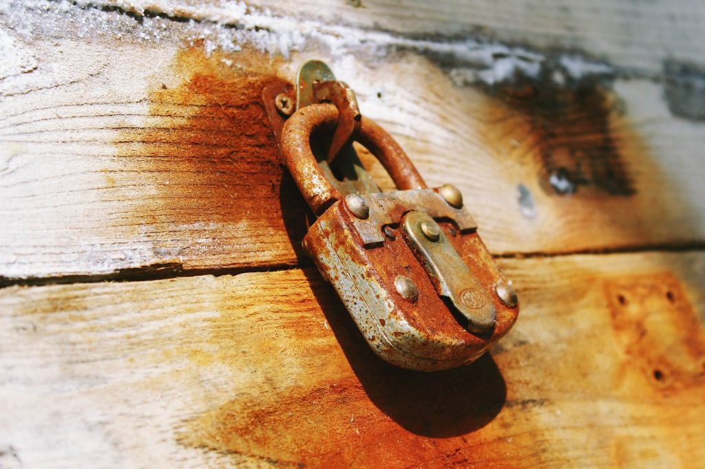 A rusty padlock on a wooden door.