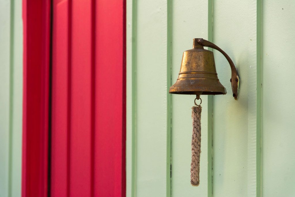 A notification bell against a green and red wall.